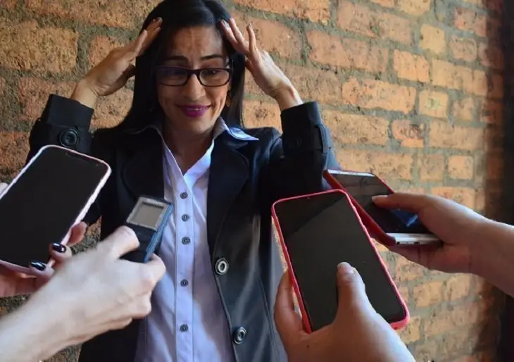 Mujer con las manos en la cabeza con varios dispositivos frente a ella